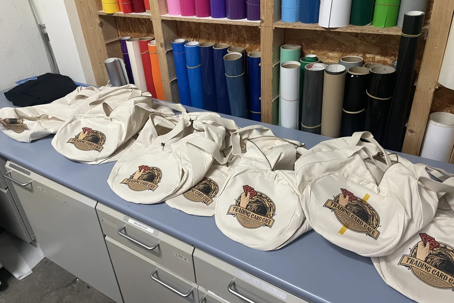Mehrere Baumwolltaschen mit mehrfarbigem Logo auf dem Arbeitstisch der Werkstatt