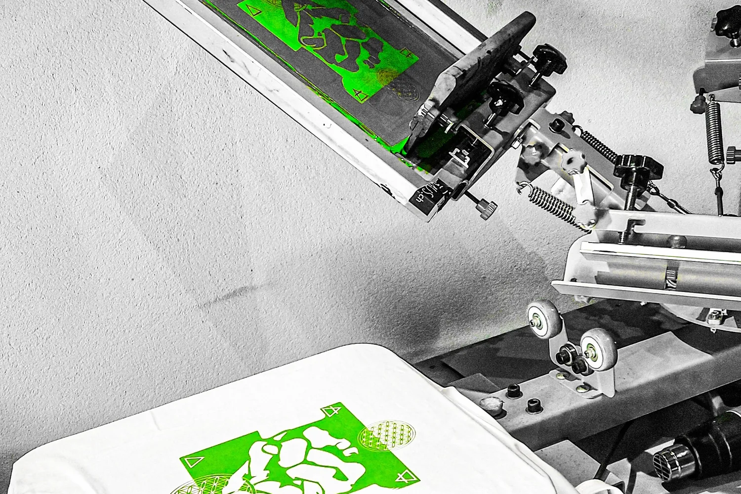 Siebdruckkarussell: grünes Motiv im Sieb, darunter das fertig bedruckte T-Shirt