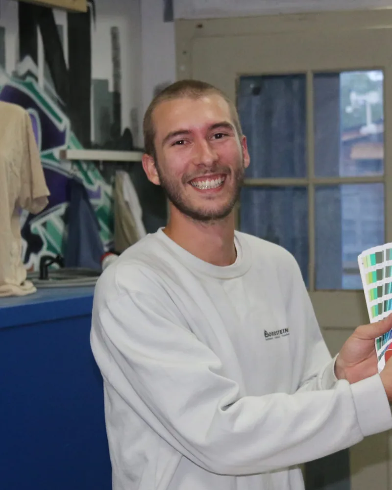 Mathis Dällenbach mit einer Farbkarte in der Werkstatt
